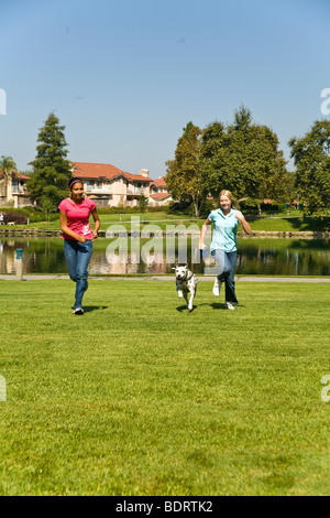 Ispanico e CaucasianTween tweens ragazze correre con un dalmata di.proprietario del cane parte anteriore USA SIGNOR © Myrleen Pearson Foto Stock