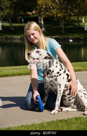 Ragazza caucasica 11-13 anni vecchio in appoggio il suo cane dalmata durante il proprietario a piedi bambino che gioca play riproduce il profilo del cane vista laterale frontale © Myrleen Pearson Foto Stock