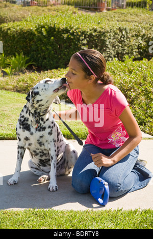 Cane ragazza 12-14 anni e anni guancia pet lecca dalmata leccare mostrando affetto proprietario si appoggia in appoggio bambino che gioca play riproduce cane vista frontale lato © Myrleen Pearson Foto Stock