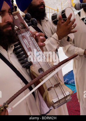 Musicista indiano la creazione di musica dal vivo su un nome a corda un Sarangi, presso il Tempio d'Oro (Sri Harmandir Sahib), Amritsar. India. Foto Stock