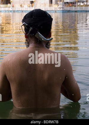 La religione sikh uomo con Kirpan nelle acque - il Sarovar (serbatoio acqua) -intorno al tempio d'Oro (Sri Harmandir Sahib) Amritsar. India. Foto Stock