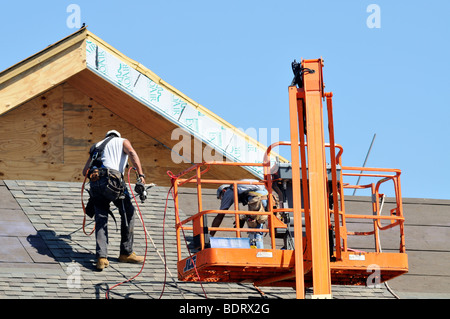 Lavoratori edili posa di tegole sul tetto esterno del nuovo edificio Foto Stock