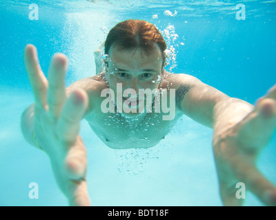 L'uomo nuotare sotto l'acqua in piscina Foto Stock