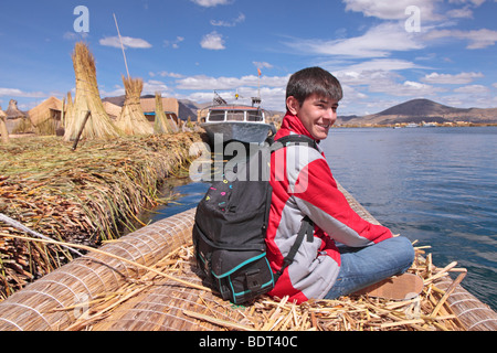 Ragazzo adolescente su imbarcazione realizzata da reed sul lago Titicaca, Puno, Perù Foto Stock