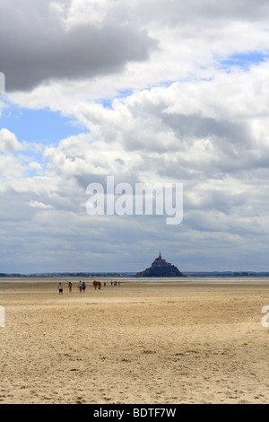 La gente camminare attraverso la sabbia con la bassa marea da Le Mont St Michel per la baia di Bec d'Andaine, Genêts Normandia Francia Foto Stock