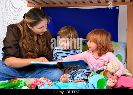 Madre la lettura di un libro per i suoi figli in un Billi-Bolli loft bed Foto Stock