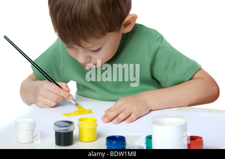 Ragazzo attira vernici su un foglio di carta, con la lingua penzoloni, isolato su bianco Foto Stock