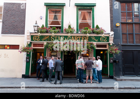 Persone di bere al di fuori della stella e Garter pub in Polonia Street nel quartiere di Soho a Londra, Inghilterra, Regno Unito Foto Stock