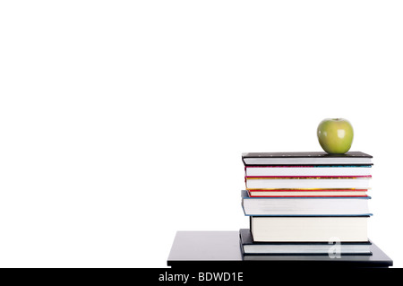 L'immagine orizzontale di una pila di libri con una mela verde su bianco Foto Stock