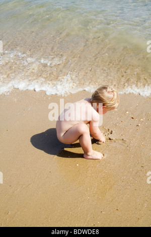 Giovane ragazzo giocando in sabbia sulla spiaggia Foto Stock