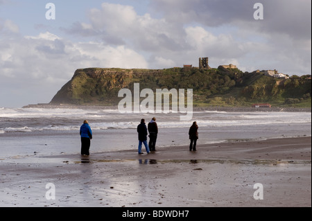 La gente camminare sulla spiaggia, North Bay, Scarborough, verso il castello sul promontorio. Foto Stock