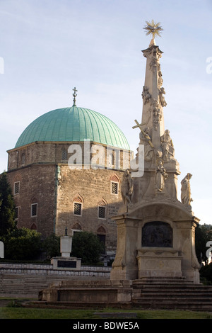 La colonna della Trinità e il Pacha Gazi Kassim moschea (noto localmente come la Moschea di chiesa) in Piazza Szchenyi a Pecs, Ungheria Foto Stock