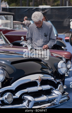 Offerente ispezionando un 1953 Packard Caraibi prima dell'impresa Gooding & Company asta durante il Concours d'Eleganza in spiaggia ghiaiosa Foto Stock