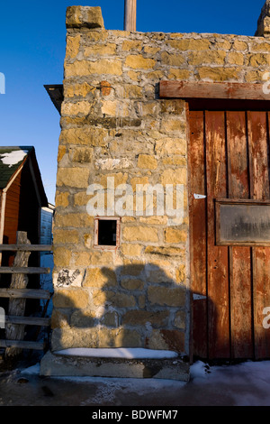 Caldo sole riflette da un vecchio ranch stone house la fusione della restante neve nel corral. Foto Stock