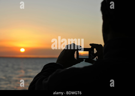 Turistica prendendo foto del tramonto con la fotocamera digitale, Urangan Porto, porto Hervey Bay, Queensland, Australia Foto Stock