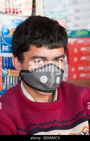 Kathmandu, Nepal. Il nepalese Book Store venditore, indossare una maschera per la respirazione per proteggere contro l'inquinamento atmosferico. Foto Stock