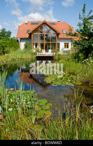 Giardino con laghetto di ninfee, nella parte anteriore della casa con giardino d'inverno, in estate Foto Stock