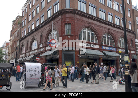 La gente camminare passato Covent Garden stazione della metropolitana in un affollato pomeriggio estivo, Covent Garden di Londra Foto Stock