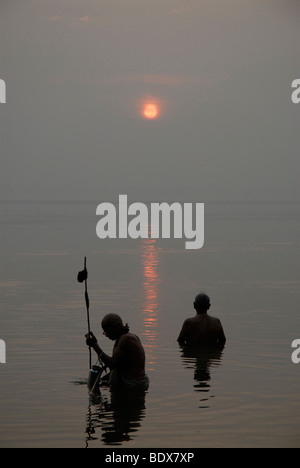 Due uomini la balneazione nel fiume Gange a sunrise. Varanasi Uttar Pradesh, India Foto Stock