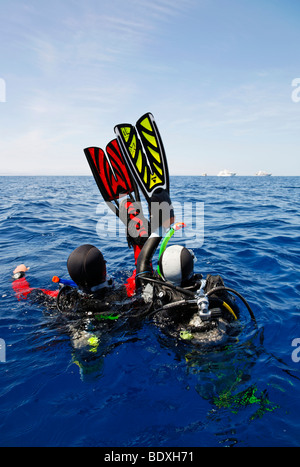 Il drifting subacquei in mare stanno tentando di ottenere l'attenzione di persone su navi di immersioni all'orizzonte agitando con le loro pinne per nuoto Foto Stock
