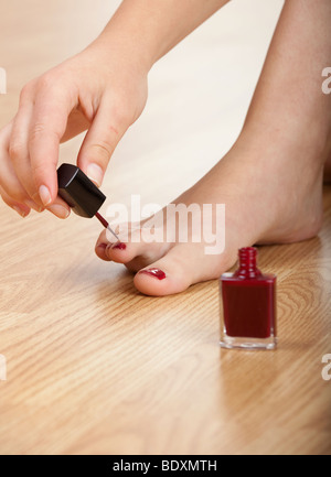 Donna colore rosso applicazione smalto per unghie isolati su se stessa Foto Stock