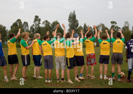 Un team di giovani uomini in pantaloncini corti con verde e giallo T-Shirt sventolando si fermò in una linea. Foto Stock