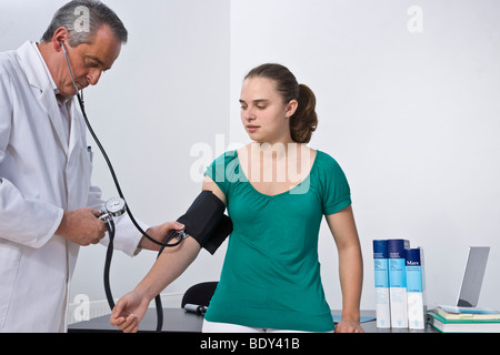 Medico la misurazione della pressione del sangue di un paziente giovane Foto Stock