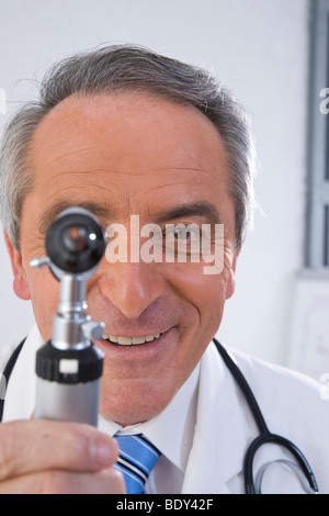 Medico sorridente guardando attraverso una lampada di medicinali Foto Stock