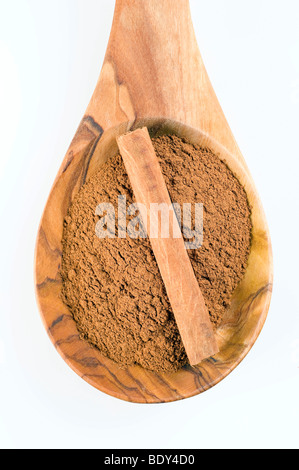 La cannella (Cinnamomum verum), in polvere e in parte di una stecca di cannella su un cucchiaio di legno d'ulivo Foto Stock