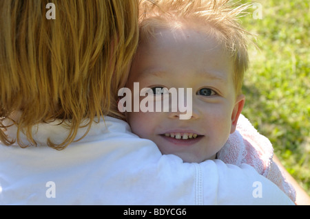 Il ragazzo, 4 anni, cuddling fino alla sua madre Foto Stock