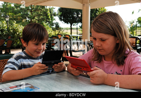 Un ragazzo e una ragazza a giocare con i loro giochi DS, a doppio schermo di giochi Foto Stock