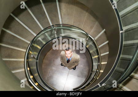 Uomo d affari al fondo delle scale a spirale Foto Stock