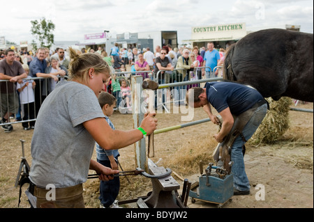 Una femmina di apprendista maniscalco facendo una horsehoe ad una fiera di paese in Essex. Foto di Gordon Scammell Foto Stock