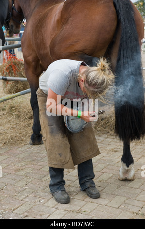 Una femmina di apprendista maniscalco montaggio di un ferro di cavallo di uno zoccolo di cavalli a un paese mostrano in Essex. Foto di Gordon Scammell Foto Stock