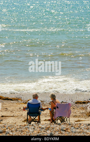 Colpo di una coppia di anziani seduti su sedie su una spiaggia Foto Stock