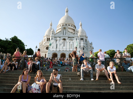 La gente seduta sui gradini della chiesa del Sacro Cuore di sera, Montmartre, Parigi, Francia Foto Stock