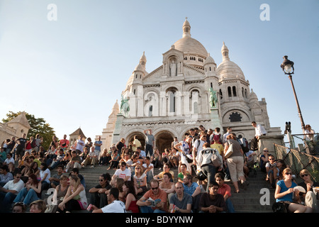 La gente seduta sui gradini della chiesa del Sacro Cuore di sera, Montmartre, Parigi, Francia Foto Stock