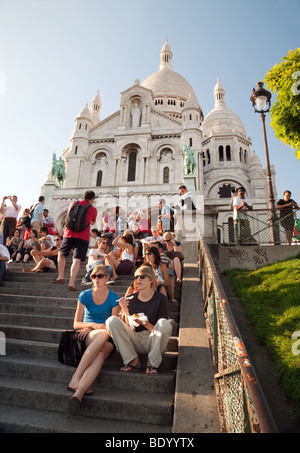 La gente seduta sui gradini della chiesa del Sacro Cuore di sera, Montmartre, Parigi, Francia Foto Stock