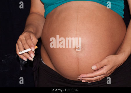 Donna incinta di fumare una sigaretta con filtro Foto Stock