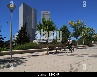 L'uomo guida una bicicletta con le torri Azrieli sullo sfondo in via Yigal Alon Tel Aviv Israele Foto Stock