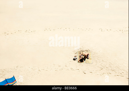 Matura a prendere il sole sulla spiaggia di sabbia bianca Foto Stock