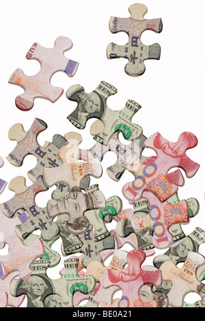 I puzzle sovrapposte con valute mondiali sparse su sfondo bianco Foto Stock
