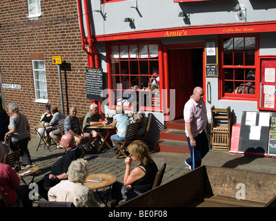 Turisti che si godono una sosta e ristoro presso i tavoli fuori Arnie's Bistro Café in luogo di mercato Whitby North Yorkshire Foto Stock