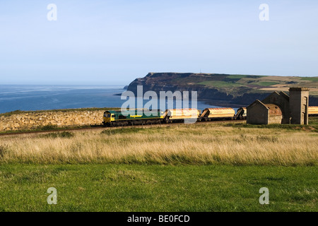 Un treno da Cleveland Potash miniera a Boulby passando il rovinato Guibal casa della ventola dall'ex Huntcliff miniera di ferro Foto Stock