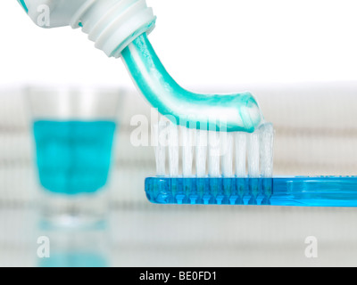 Un blu spazzolino da denti con dentifricio. Il collutorio e asciugamani sullo sfondo Foto Stock