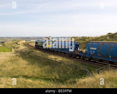 Un treno in direzione di Cleveland Potash miniera a Boulby passando il rovinato Guibal casa della ventola dall'ex Huntcliff miniera di ferro Foto Stock