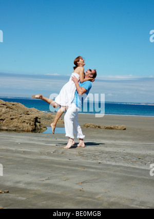 Uomo Donna di sollevamento in aria sulla spiaggia Foto Stock