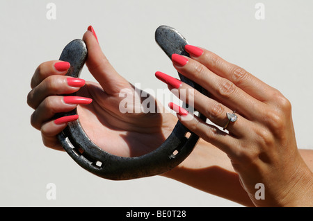 Womans mani con red Nail Polish tenendo un vecchio ferro di cavallo Foto Stock