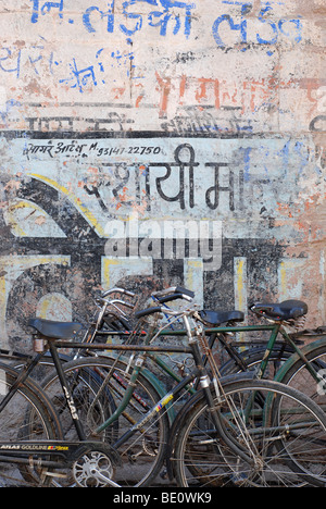 Biciclette parcheggiate in parete dipinta, Jodhpur, Rajasthan, India Foto Stock