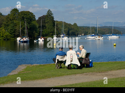 Tre persone rilassante cadde in piedi Park, Lago di Windermere, Parco Nazionale del Distretto dei Laghi, Cumbria, England Regno Unito Foto Stock